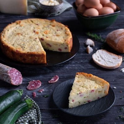 Torta salata di pane con una fetta tagliata che rivela il ripieno con salame e zucchine