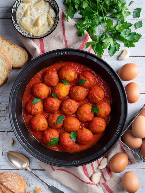 Pallotte cacio e ova in salsa di pomodoro, guarnite con foglie di prezzemolo fresco
