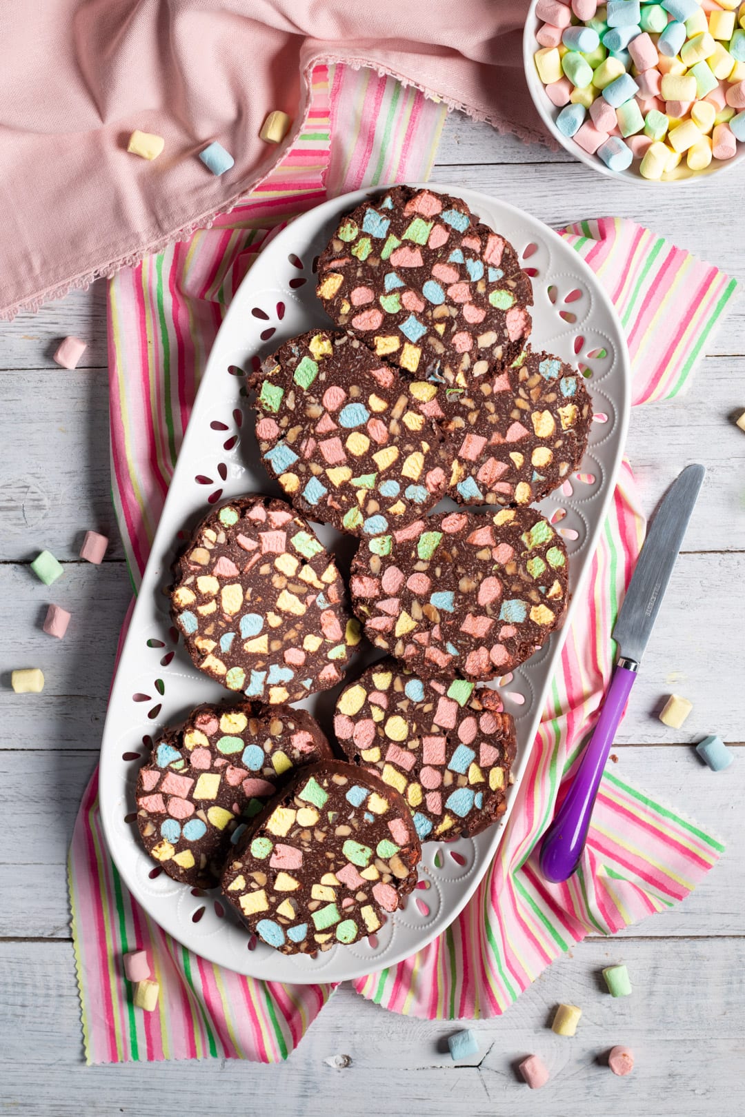 Fette di salame di cioccolato con marshmallow colorati disposte su un vassoio