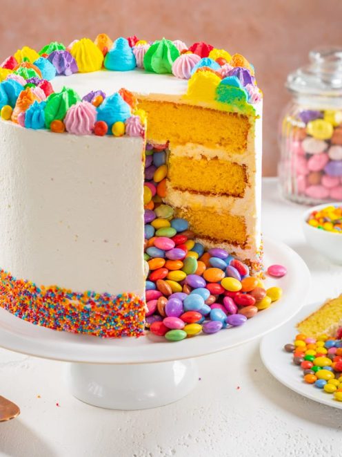 Torta sorpresa di compleanno a strati con confetti colorati che fuoriescono dalla fetta tagliata