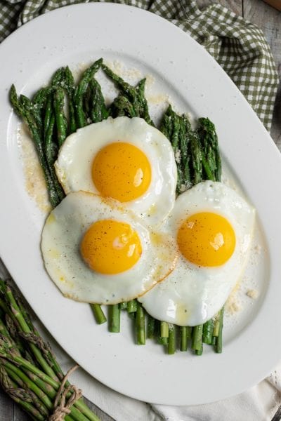 Asparagi alla milanese con tre uova in cereghin adagiate sugli asparagi e spolverata di parmigiano