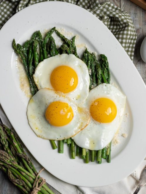 Asparagi alla milanese con tre uova in cereghin adagiate sugli asparagi e spolverata di parmigiano