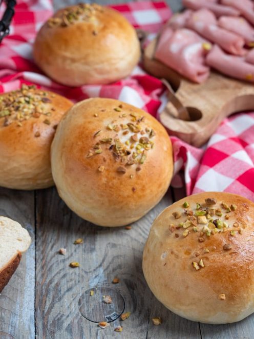 Bombe ripiene di provola e mortadella con granella di pistacchio in superficie, una tagliata a metà rivela il ripieno