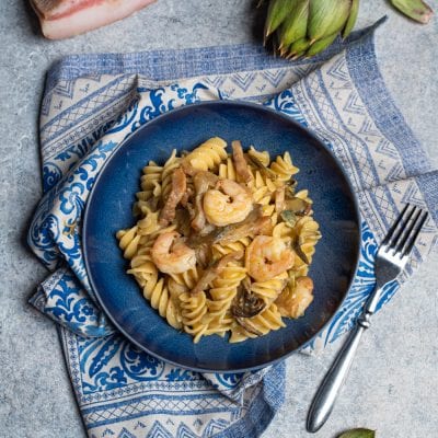 Carbonara di carciofi con fusilli, gamberi e strisce di guanciale in salsa cremosa