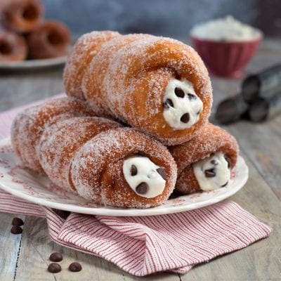 Cartocci siciliani fritti ricoperti di zucchero, farciti con crema di ricotta e gocce di cioccolato