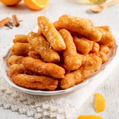 Crispelle al miele dorate e fritte, lucide di miele e impilate su un vassoio