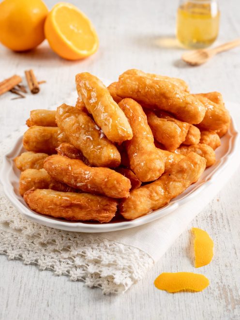 Crispelle al miele dorate e fritte, lucide di miele e impilate su un vassoio