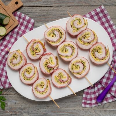 Girelle di pollo farcite con zucchine e formaggio, infilzate su spiedini e servite su vassoio
