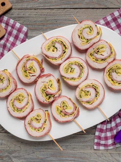 Girelle di pollo farcite con zucchine e formaggio, infilzate su spiedini e servite su vassoio
