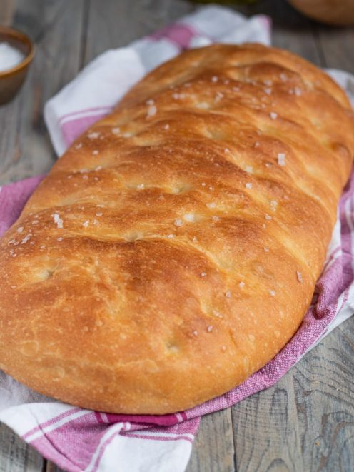 Pan focaccia dalla crosta dorata e croccante, cosparso di fiocchi di sale grosso