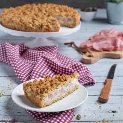 Sbriciolata salata con mortadella, groviera e ricotta: una fetta mostra il ripieno cremoso sotto la frolla sbriciolata