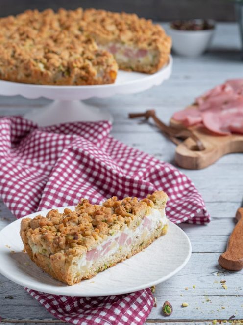 Sbriciolata salata con mortadella, groviera e ricotta: una fetta mostra il ripieno cremoso sotto la frolla sbriciolata