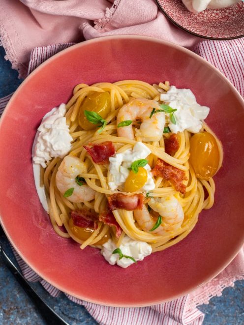 Spaghetti alla chitarra con gamberi, burrata, pomodorini gialli e pancetta croccante guarniti con basilico