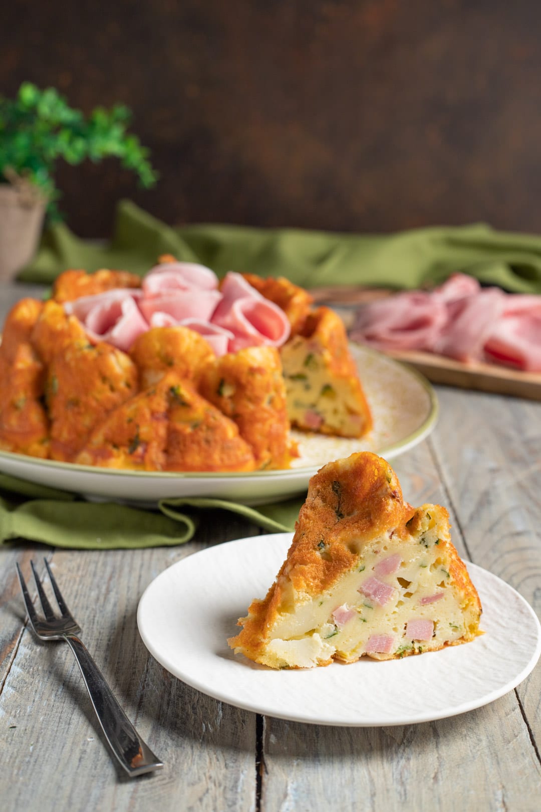 Fetta di ciambella salata con prosciutto cotto e zucchine, con l'impasto morbido ben visibile