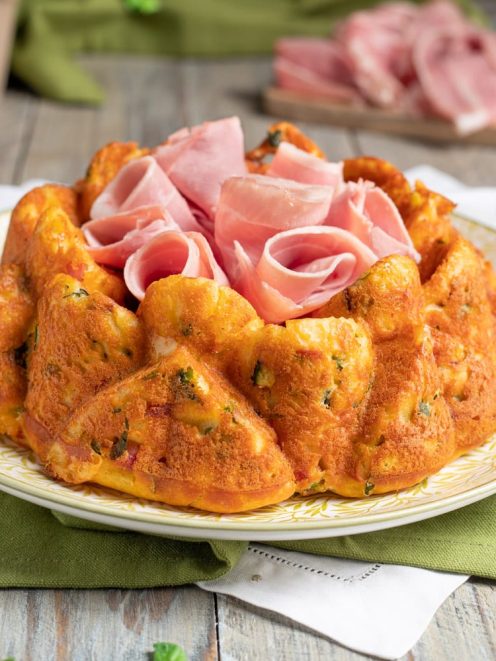 Ciambella salata con prosciutto cotto e zucchine, dorata e soffice, con fette di prosciutto arrotolate al centro
