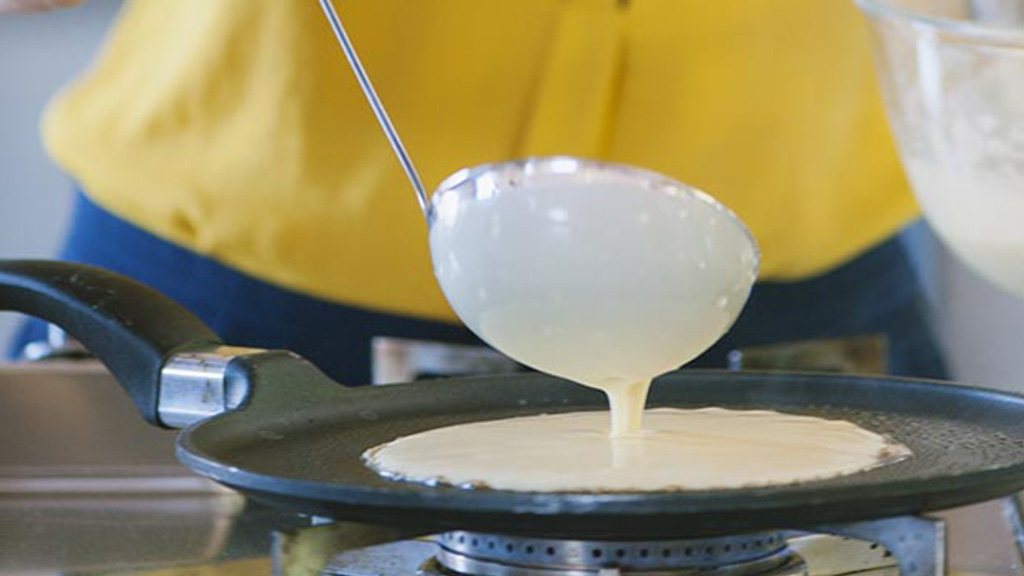 Burro che sfrigola sul fondo della padella mentre viene versata la pastella per crepe