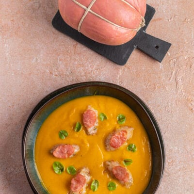 Vellutata fredda di zucca con bocconcini di gamberi, fette di salame e foglioline verdi