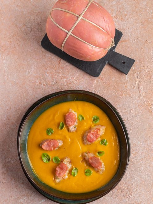 Vellutata fredda di zucca con bocconcini di gamberi, fette di salame e foglioline verdi