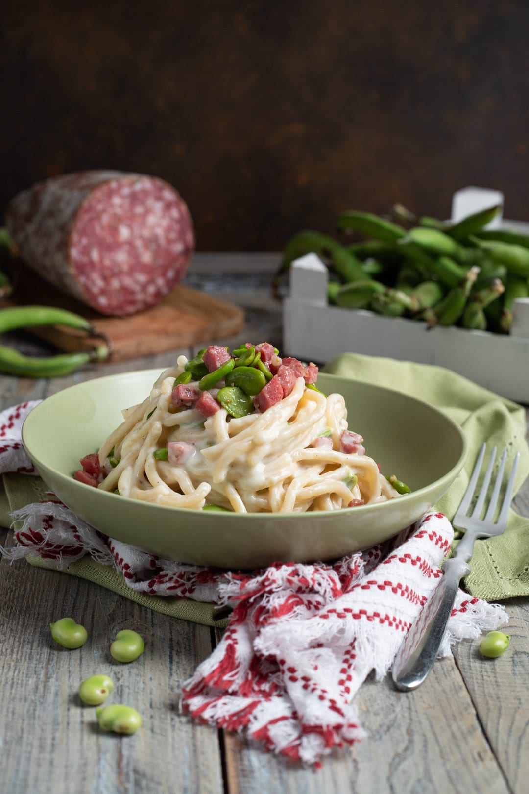 Pici mantecati con crema di pecorino, fave fresche e cubetti di finocchiona nel piatto