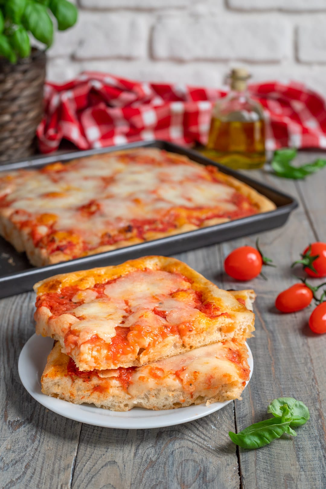 Due fette di pizza in teglia sovrapposte, con salsa di pomodoro e mozzarella filante