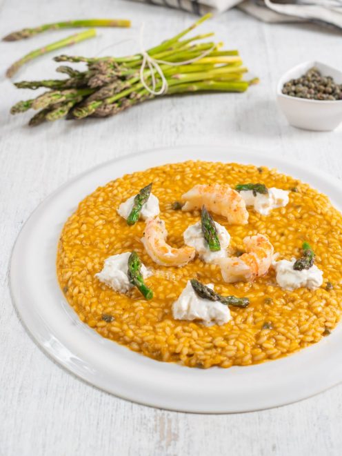 Risotto con scampi, burrata e asparagi selvatici su fondo dorato e cremoso