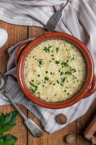 Stracciatella alla romana in cocotte di terracotta, cosparsa di parmigiano grattugiato e prezzemolo tritato