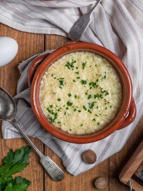 Stracciatella alla romana in cocotte di terracotta, cosparsa di parmigiano grattugiato e prezzemolo tritato