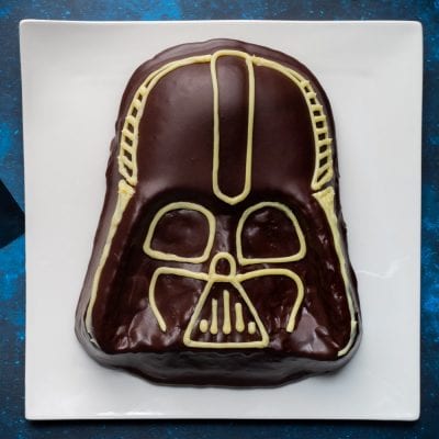 Torta Star Wars a forma di casco di Darth Vader glassata al cioccolato fondente con decorazioni in cioccolato bianco