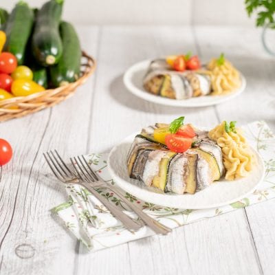 Tortini di alici con hummus alla menta guarniti con pomodorini e foglie di basilico