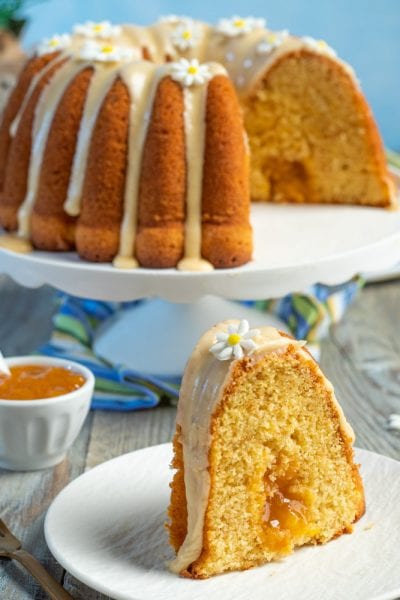 Ciambella alle pesche con glassa e farciture di confettura, decorata con fiorellini di zucchero