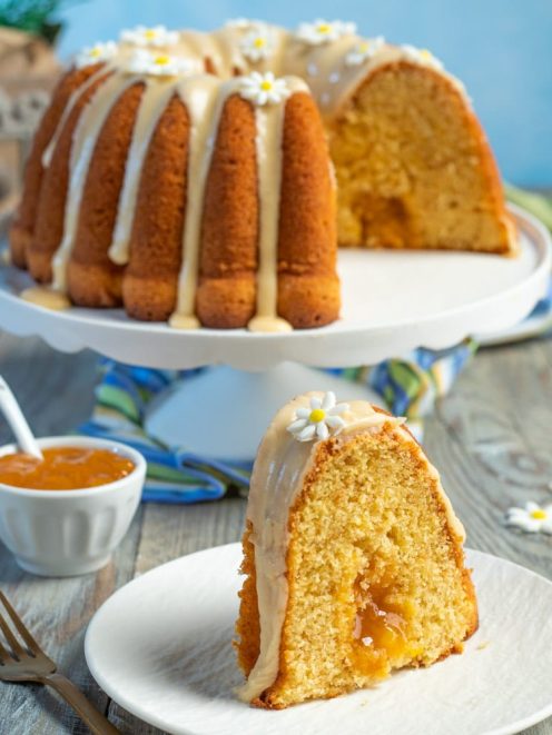 Ciambella alle pesche con glassa e farciture di confettura, decorata con fiorellini di zucchero