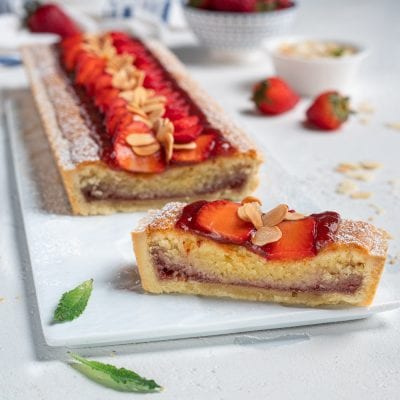 Crostata con crema frangipane e confettura, guarnita con fragole fresche e lamelle di mandorle tostate