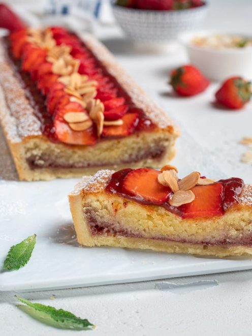 Crostata con crema frangipane e confettura, guarnita con fragole fresche e lamelle di mandorle tostate