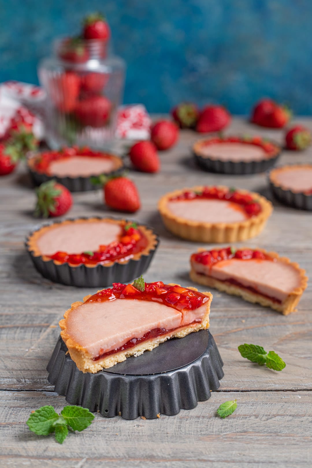 Crostatine con panna cotta alle fragole decorate con confettura, fragole a cubetti e foglioline di menta