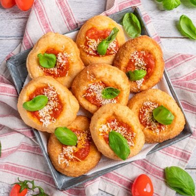 Montanare fritte con salsa di pomodoro, formaggio grattugiato e foglie di basilico fresco