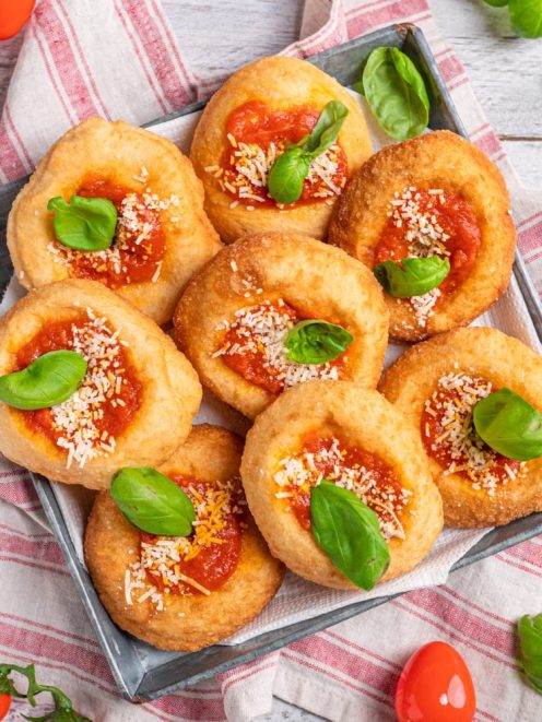 Montanare fritte con salsa di pomodoro, formaggio grattugiato e foglie di basilico fresco
