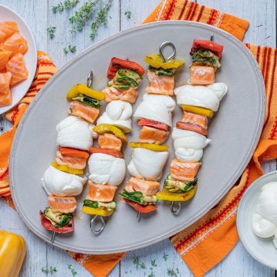 Spiedini con nodini di mozzarella, salmone e verdure grigliate serviti su vassoio