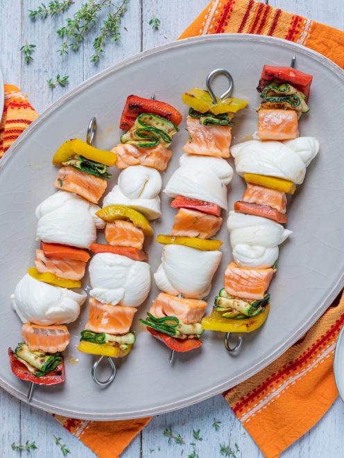 Spiedini con nodini di mozzarella, salmone e verdure grigliate serviti su vassoio