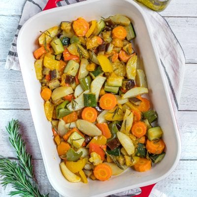 Verdure al forno con carote, zucchine, patate e peperoni profumate al rosmarino in teglia