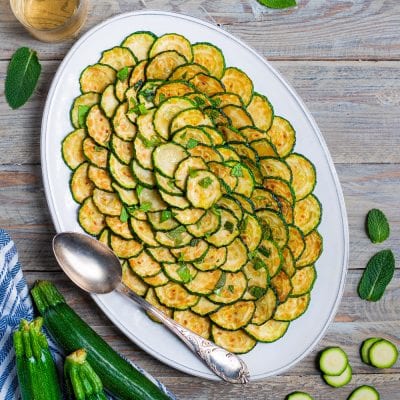 Zucchine scapece a rondelle fritte disposte a spirale, guarnite con foglie di menta fresca