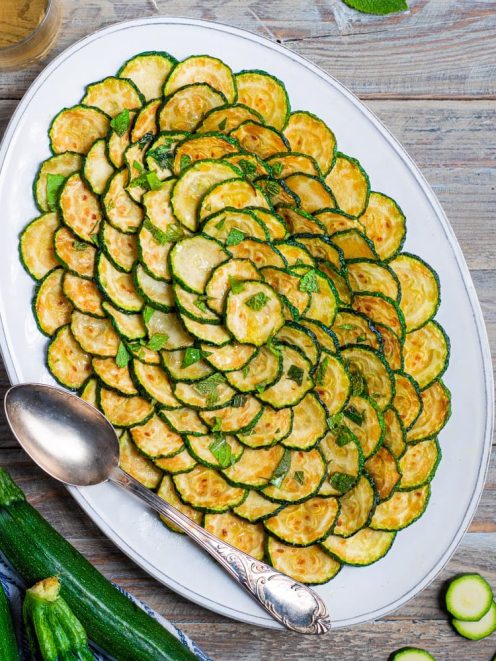 Zucchine scapece a rondelle fritte disposte a spirale, guarnite con foglie di menta fresca