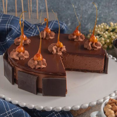 Cheesecake al cioccolato con glassa lucida, pannelli di cioccolato fondente e decorazioni di caramello soffiato