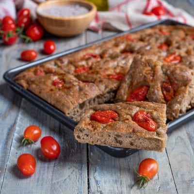 Focaccia ai cereali con pomodorini tagliata a fette, con la mollica alveolata ben visibile