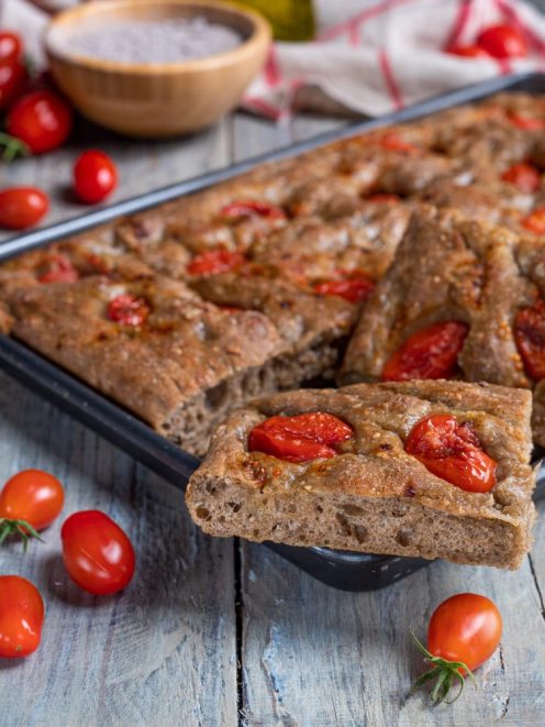 Focaccia ai cereali con pomodorini tagliata a fette, con la mollica alveolata ben visibile