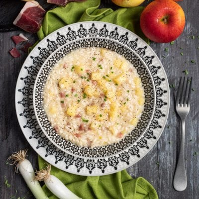 Risotto speck e mele con cubetti di mela, pezzetti di speck, pepe nero e erba cipollina