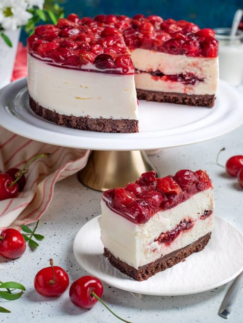 Cheesecake alle ciliegie con base al cioccolato, crema bianca e topping di ciliegie sciroppate, servita a fetta