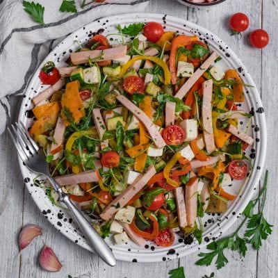 Insalata di tacchino con rucola, pomodorini, peperoni grigliati, zucchine e cubetti di formaggio