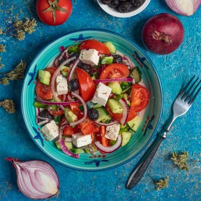 Insalata greca con pomodori, cetrioli, feta a cubetti, olive nere e cipolla rossa