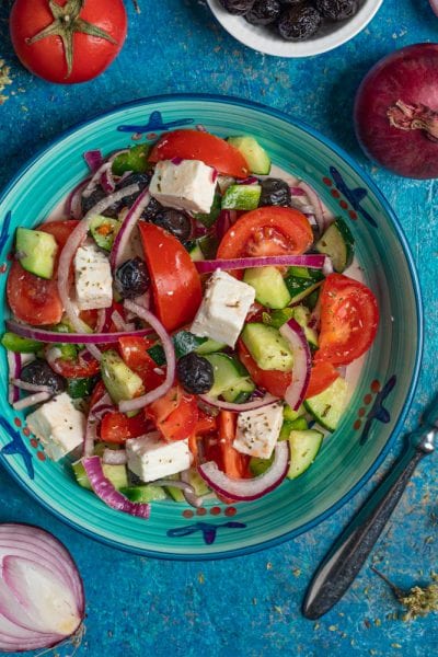 Insalata greca con pomodori, cetrioli, feta a cubetti, olive nere e cipolla rossa