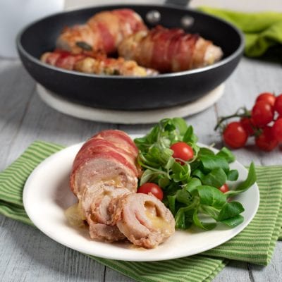 Involtini di tacchino avvolti nella pancetta, affettati e serviti con valeriana e pomodorini ciliegino